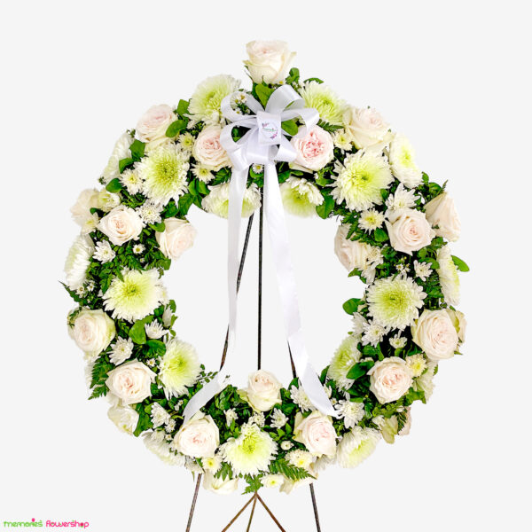 Corona funeraria con rosas ecuatorianas blancas, crisantemos, gypsophila, centro verde y follajes